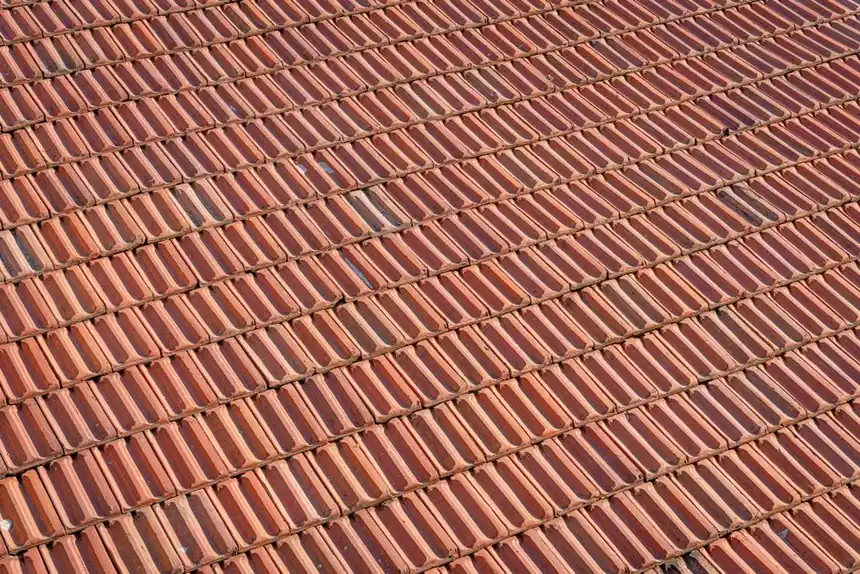Aerial view of a textured red clay tile roof with a repeating pattern.