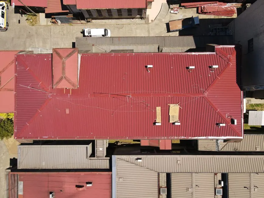 Aerial view showcasing vibrant red metal rooftops in a city, highlighting architectural patterns and urban organization.