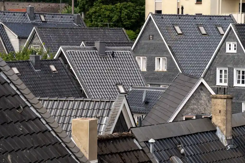 Aesthetic overhead view of gray tiled rooftops in a quaint residential neighborhood with lush greenery.