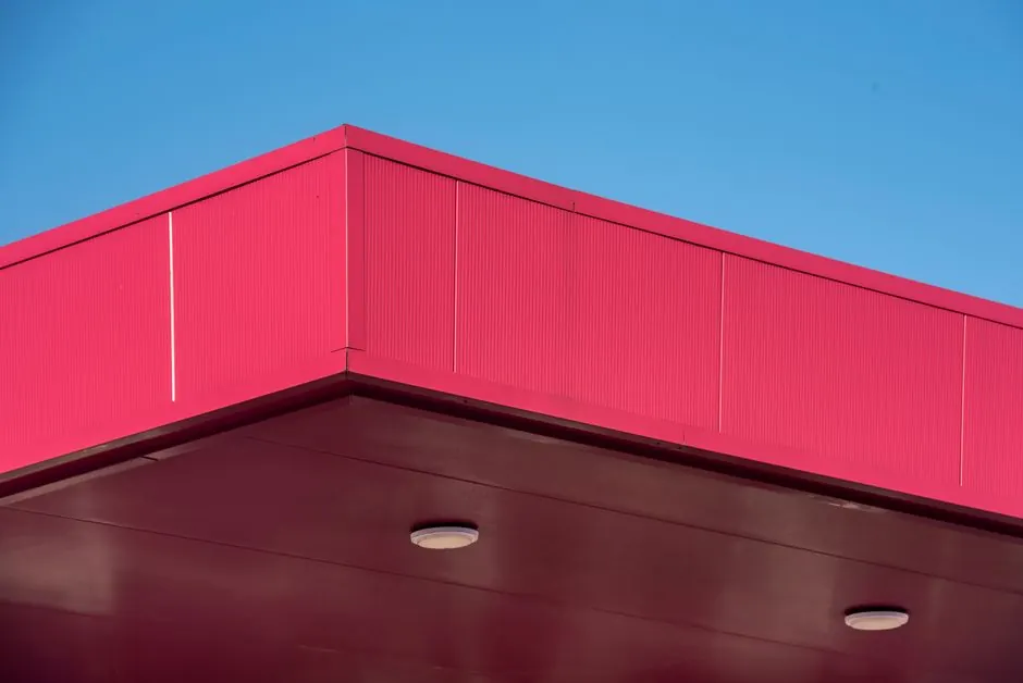 Close-up of a red building roof with a minimalistic architectural design under a clear blue sky.