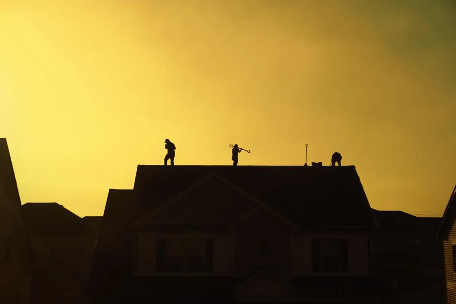 Silhouette of construction workers repairing a roof at sunset in Clarksville, Tennessee.