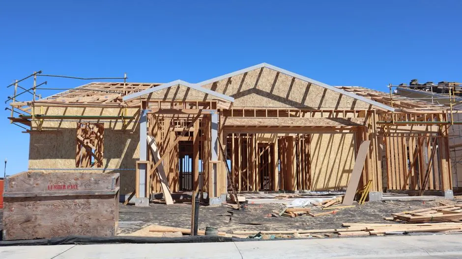 Wooden frame construction of a new residential home under clear blue sky.